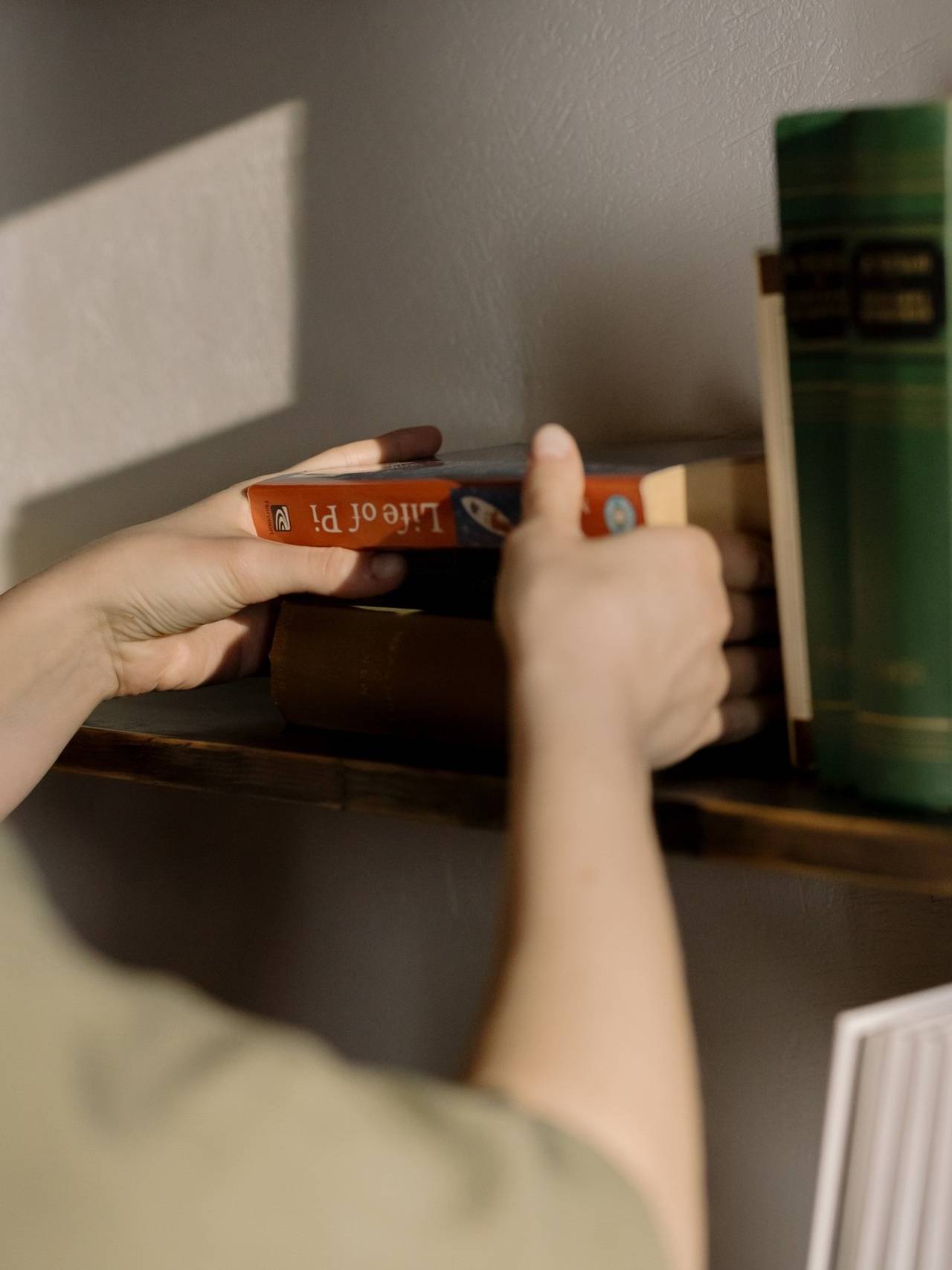 Mãos segurando livro e colocando ele na horizontal em uma pilha de livros